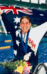 Australian S8 swimmer Priya Cooper on the pool deck with the Australian flag, gold medal and flowers after a medal presentation ceremony at the 1996 Atlanta Paralympic Games