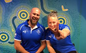 An image of Ryley Batt and Danni Di Toro in official merchandise of Paralympics Australia. Both of them are smiling and Danni is flashing a victory sign for the camera.