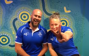 An image of Ryley Batt and Danni Di Toro in official merchandise of Paralympics Australia. Both of them are smiling and Danni is flashing a victory sign for the camera.