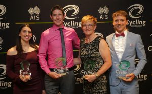 An image of four para-cyclists in an award ceremony, holding their awards and smiling