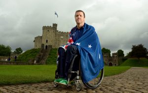 Male Paralympian Greg Smith in a wheelchair draped in the Australian flag