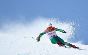 Image of male skier wearing a green ski suit with a white and red competitor bib.