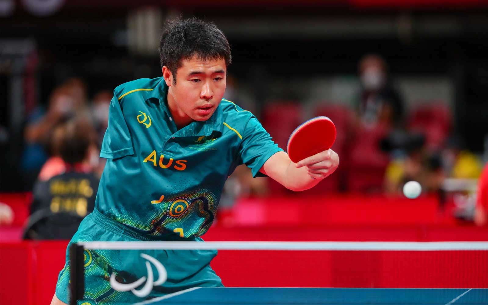 Male Para-table tennis player lean in to hit a ball with his paddle