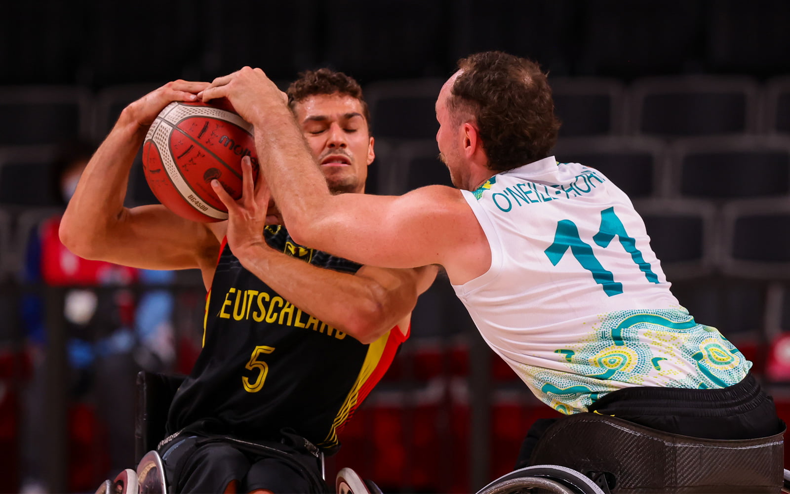 Two male Wheelchair basketball players wrestling over a ball
