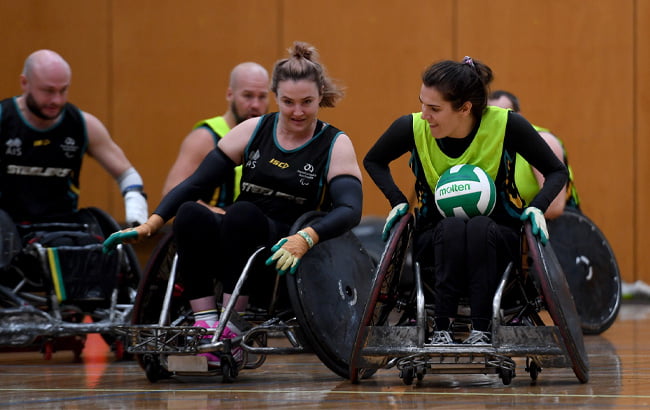 Shae Graham and Ella Sabljak training for Wheelchair rugby. The ball is in Ella's lap.